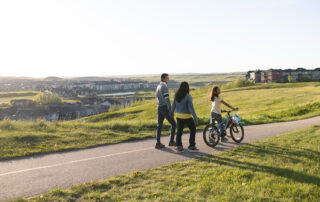 Family biking together along a picturesque pathway in Ambleridge, showcasing active outdoor living and connected green spaces.