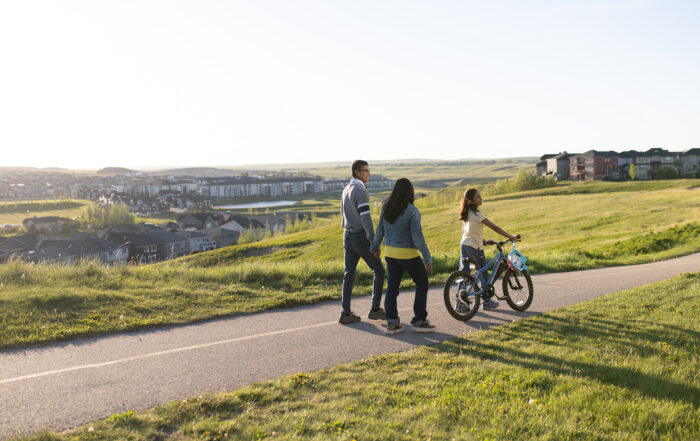 Family biking together along a picturesque pathway in Ambleridge, showcasing active outdoor living and connected green spaces.