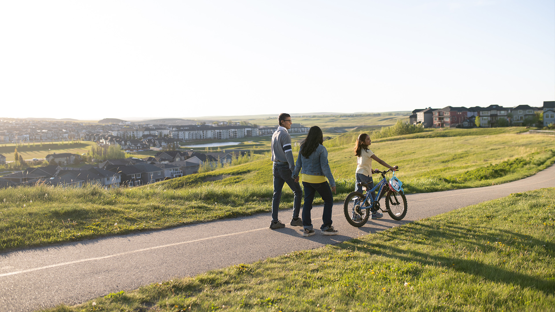 Family biking together along a picturesque pathway in Ambleridge, showcasing active outdoor living and connected green spaces.