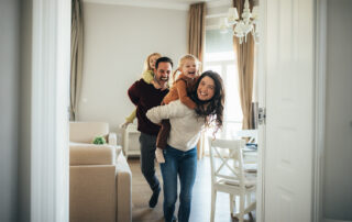 Smiling family enjoying quality time together with parents giving their children piggyback rides in their home